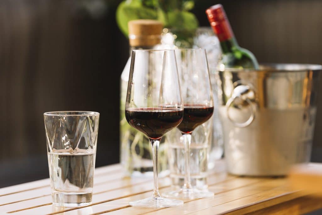 two red wine glasses glass water wooden table